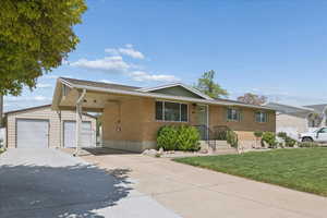 Ranch-style home with an outbuilding, a front lawn, brick siding, concrete driveway, and an attached carport
