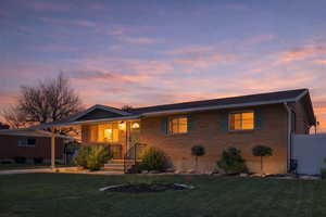 Single story home featuring a yard, a porch, brick siding, and a carport