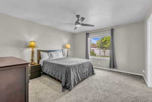 Carpeted bedroom featuring baseboards and ceiling fan