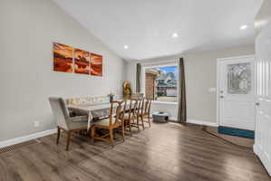 Dining space featuring vaulted ceiling, dark wood finished floors, and recessed lighting