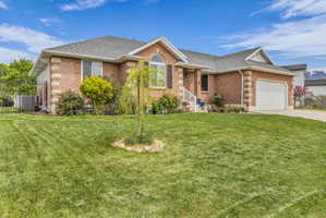 Single story home featuring brick siding, a shingled roof, an attached garage, and driveway