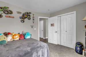 Bedroom with dark colored carpet and a closet