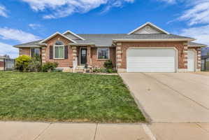 Single story home featuring roof with shingles, an attached garage, and brick siding