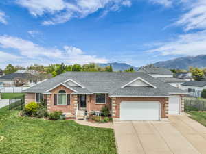 Single story home with roof with shingles, an attached garage, driveway, and brick siding