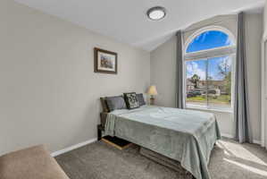 Bedroom with carpet floors and vaulted ceiling