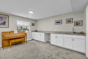Kitchen featuring white cabinetry, light colored carpet, and light stone countertops
