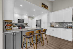 Kitchen with a peninsula, a kitchen bar, light stone counters, recessed lighting, and stainless steel appliances