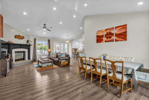 Dining room with a glass covered fireplace, ceiling fan, lofted ceiling, dark wood-style flooring, and recessed lighting