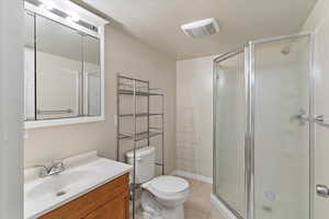 Full bathroom featuring vanity, a textured ceiling, a shower stall, and light tile patterned floors