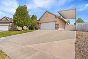 View of front of property featuring a gate, stucco siding, an attached garage, driveway, and stone siding