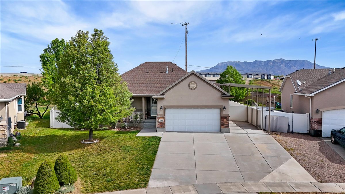 View of front of property featuring stucco siding, a residential view, an attached garage, concrete driveway, and a gate