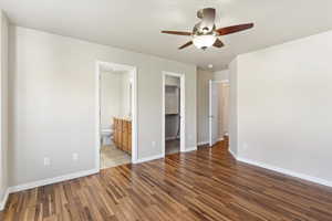 Primary Bedroom featuring a spacious closet, dark wood-type flooring, a ceiling fan, and ensuite bath