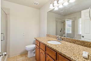 Primary bathroom with a shower stall, vanity, and light tile patterned floors