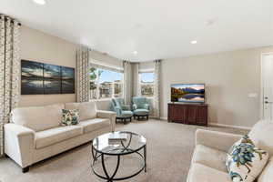 Living area with light carpet and recessed lighting