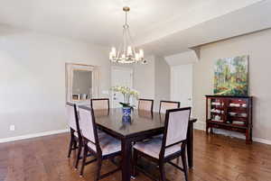 Dining room featuring dark wood-style flooring and a chandelier