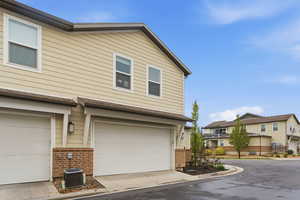 View of property exterior featuring brick siding, a garage, a residential view, and driveway