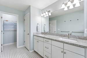 Full bathroom with double vanity and baseboards