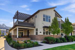 View of front facade with brick siding and a pergola
