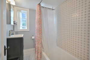 Bathroom with vanity, shower / bath combination, and light tile patterned floors