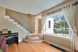 Stairway featuring curved metal handrailing, and hardwood flooring