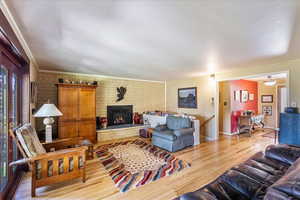 Living area featuring light wood-style flooring, a fireplace, and ornamental molding