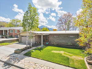 Single story home with a chimney, a mountain view, brick siding, and a garage