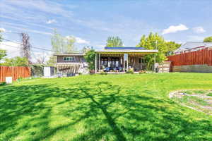 Back of property featuring a fenced backyard, a patio area, solar panels, and a chimney