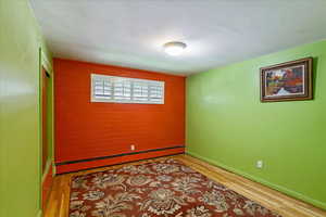 Empty room with a baseboard radiator and light wood finished floors