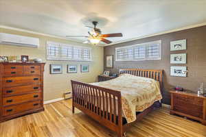 Bedroom with light wood-style floors, crown molding, a ceiling fan, and a baseboard radiator