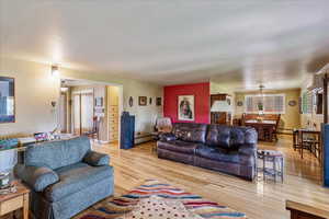 Living room featuring light wood-type flooring, a ceiling fan, and baseboard heating