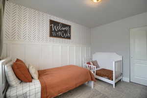 Bedroom featuring wallpapered walls, a decorative wall, a wainscoted wall, and carpet
