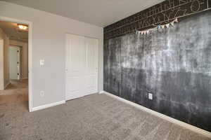 Unfurnished bedroom featuring dark carpet and a closet