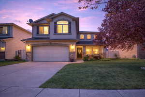 Traditional-style house with an attached garage, concrete driveway, stone siding, and stucco siding