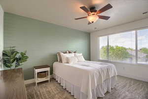 Bedroom with wood walls, carpet flooring, and ceiling fan