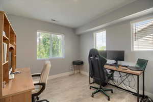 Home office with light wood-style flooring and plenty of natural light