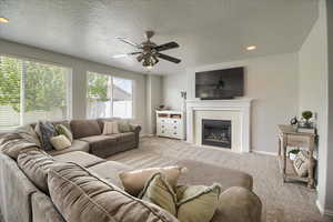 Living area with carpet floors, a textured ceiling, a tile fireplace, ceiling fan, and recessed lighting