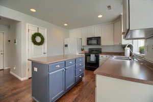 Kitchen featuring dual tone cabinetry, black appliances, dark wood-style flooring, a kitchen island, and recessed lighting