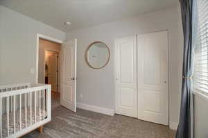 Unfurnished bedroom with dark carpet, a crib, and a closet