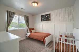 Bedroom with wallpapered walls, a decorative wall, a wainscoted wall, and carpet flooring