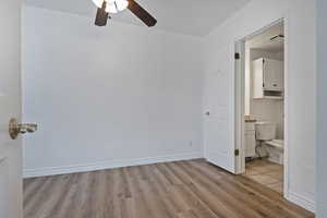 Unfurnished bedroom featuring light wood-type flooring, ceiling fan, and ensuite bath