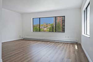 Empty room with a baseboard heating unit and wood finished floors