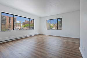 Unfurnished room with a baseboard heating unit and dark wood finished floors