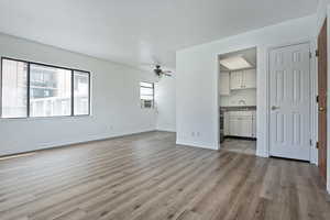 Unfurnished living room with ceiling fan, light wood-style floors, and cooling unit