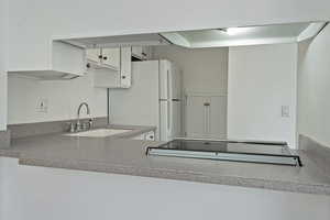 Kitchen featuring white cabinetry and freestanding refrigerator