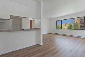 Unfurnished living room featuring dark wood-type flooring and baseboard heating