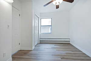 Unfurnished bedroom with light wood-style flooring, a baseboard radiator, a closet, and ceiling fan