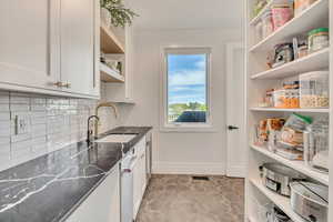 Kitchen featuring white cabinetry, dishwasher, decorative backsplash, and open shelves