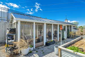 View of patio featuring a sunroom, an outbuilding, and exterior structure