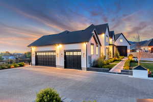 View of front of home featuring decorative driveway, a garage, and brick siding