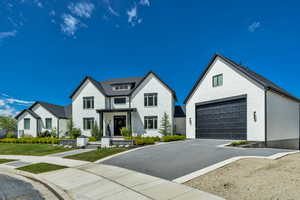 Modern farmhouse featuring driveway, brick siding, and an outbuilding